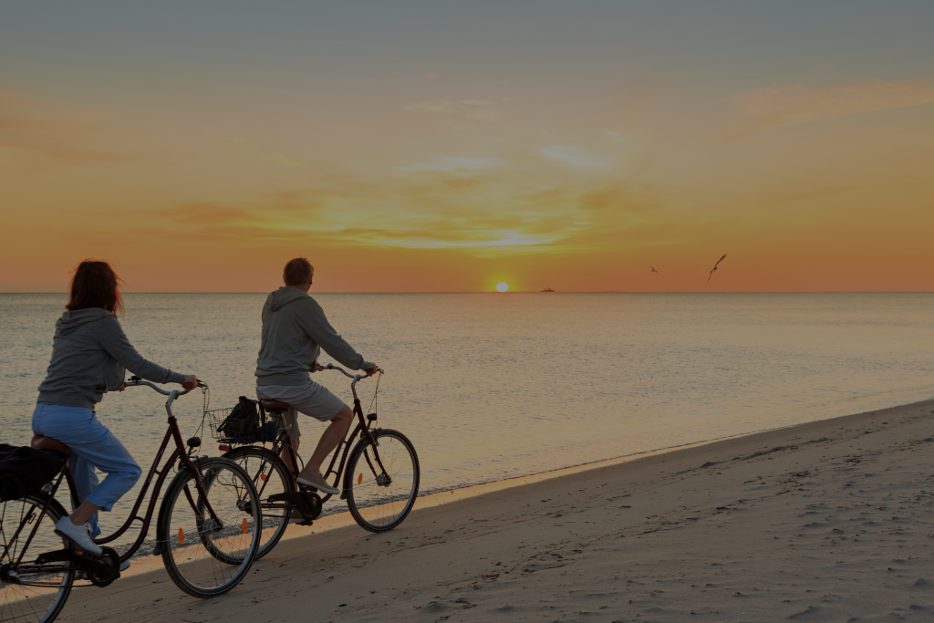 retirement couple on bikes on beach
